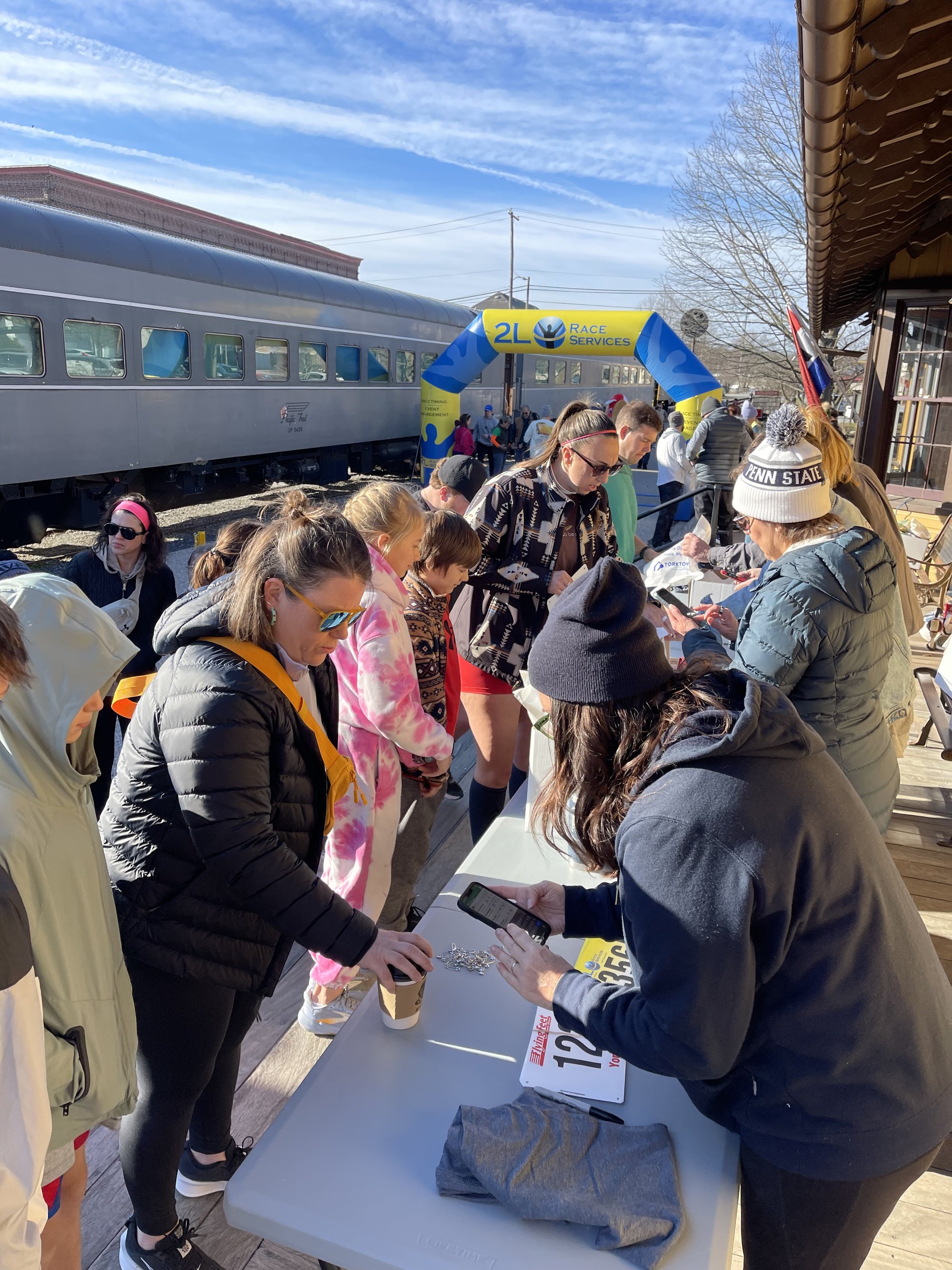 Racers checking in at the registration table on the New Freedom station platform, with the train behind them